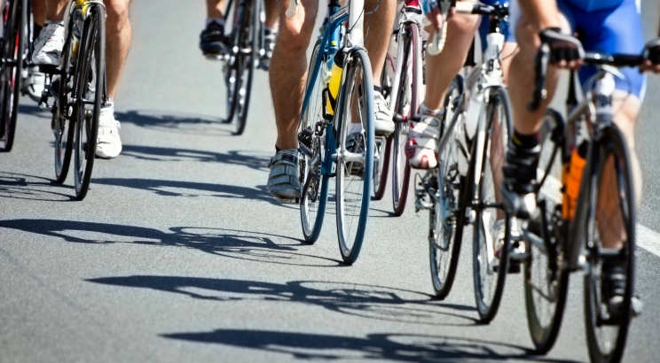 A low-angle shot of a group of cyclists riding closely together in a peloton during a road bicycle race.